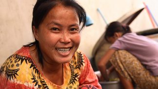 Cambodian woman prepares food for her family while her daughter looks on