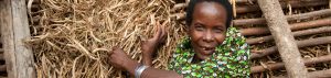 A Ugandan woman smiles as she shows off her crop of beans, dried for storage